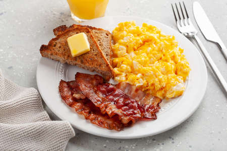 traditional scrambled egg breakfast with bacon and toastの写真素材