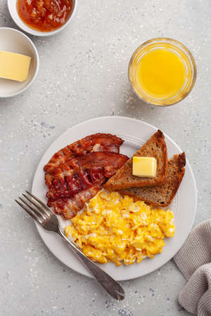 traditional scrambled egg breakfast with bacon and toastの写真素材