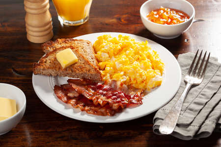 traditional scrambled egg breakfast with bacon and toastの写真素材