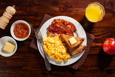 traditional scrambled egg breakfast with bacon and toastの写真素材