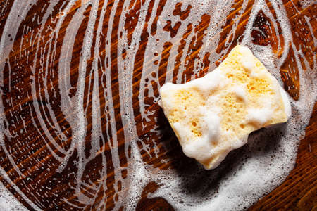 cleaning sponge wiping foam soap suds on wooden background, household washing conceptの写真素材