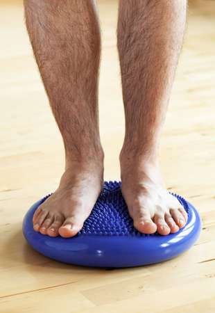 man doing flatfoot correction gymnastic exercise balancing on massage cushion at homeの写真素材