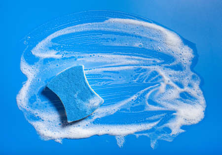 cleaning sponge wiping foam soap suds on blue background, household washing conceptの写真素材