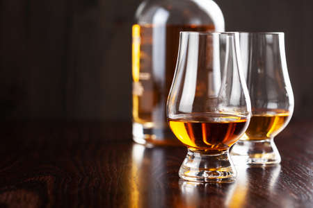 Bottle and glass of whisky spirit brandy on dark brown backgroundの写真素材
