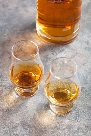 glass and bottle of whisky spirit brandy on gray concrete backgroundの写真素材