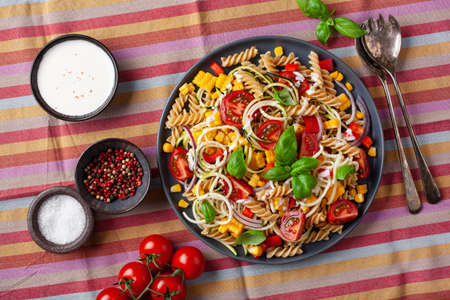 healthy pasta salad with zucchini sweet corn tomato and basil, vegetarian lunchの写真素材