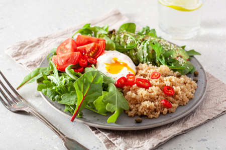 quinoa with poached egg, avocado tomato salad leaves. healthy vegetarian lunch breakfastの写真素材