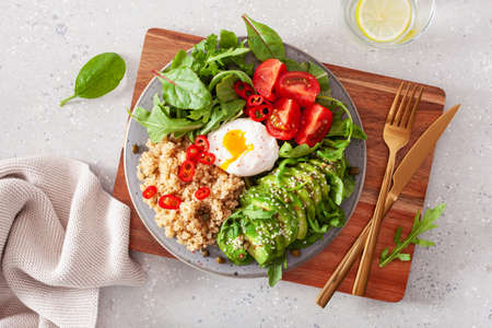 quinoa with poached egg, avocado tomato salad leaves. healthy vegetarian lunch breakfastの写真素材