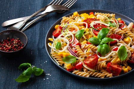 healthy pasta salad with zucchini sweet corn tomato and basil, vegetarian lunchの写真素材