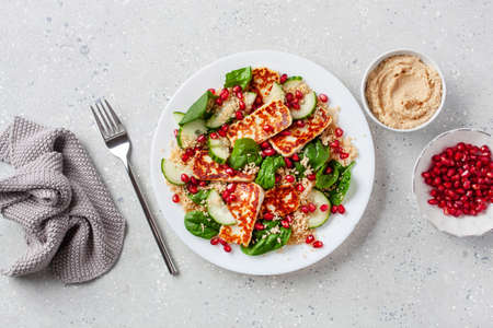 healthy halloumi cheese and couscous salad with cucumber spinach pomegranate hummusの写真素材