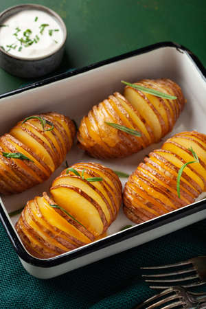 baked hasselback potato with cheddar cheese and rosemaryの写真素材