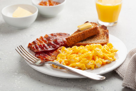 traditional scrambled egg breakfast with bacon and toastの写真素材