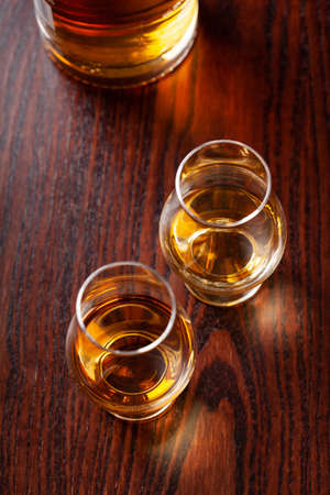 Bottle and glass of whisky spirit brandy on dark brown backgroundの写真素材