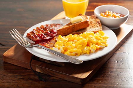 traditional scrambled egg breakfast with bacon and toastの写真素材