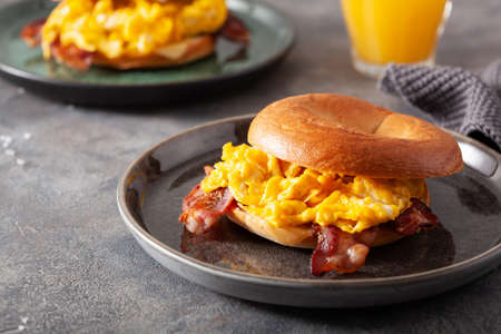 breakfast egg and bacon sandwich on bagel with cheeseの写真素材