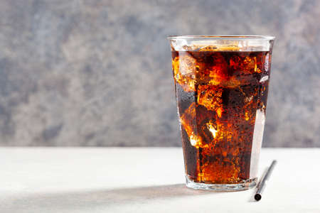 glass of cold cola soft drink with ice on wooden backgroundの写真素材