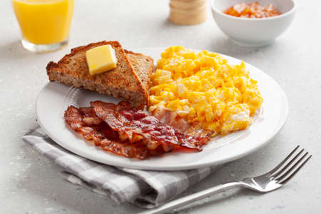 traditional scrambled egg breakfast with bacon and toastの写真素材