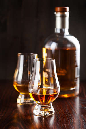 Bottles and glass of whisky spirit brandy on dark brown backgroundの写真素材
