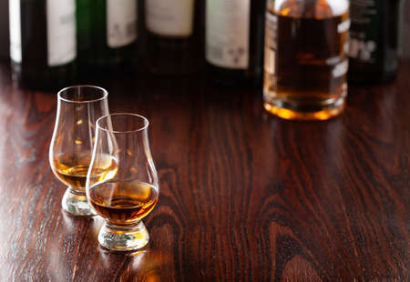 Bottles and glass of whisky spirit brandy on dark brown backgroundの写真素材
