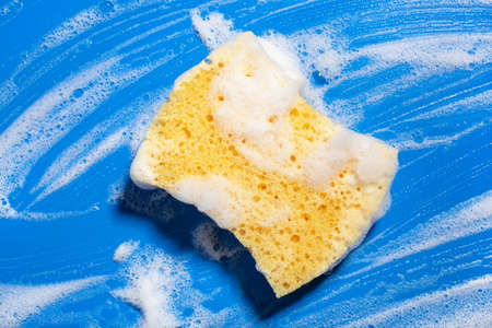 cleaning sponge wiping foam soap suds on blue background, household washing conceptの写真素材