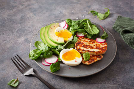 healthy keto paleo diet breakfast: boiled egg, avocado, halloumi cheese, salad leavesの写真素材