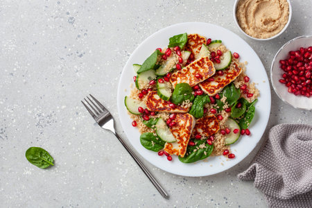 healthy halloumi cheese and couscous salad with cucumber spinach pomegranate hummusの写真素材