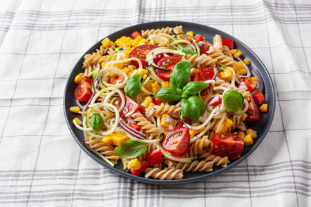healthy pasta salad with zucchini sweet corn tomato and basil, vegetarian lunchの写真素材