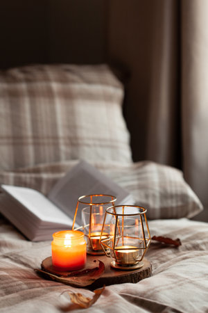 warm cozy bedroom winter or autumn concept, candles on tray and a book