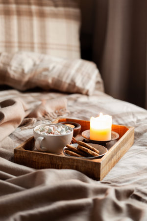 warm cozy bedroom winter or autumn concept, cup of hot chocolate on tray, candles throwの写真素材