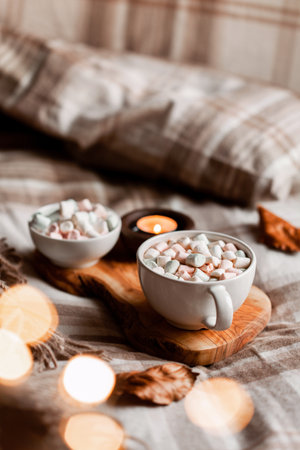 warm cozy bedroom winter or autumn concept, cup of hot chocolate on tray, candles throwの写真素材