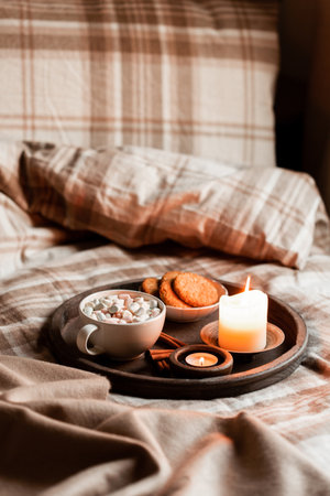Warm cozy bedroom interior with cup of hot chocolate on tray, candlesの写真素材