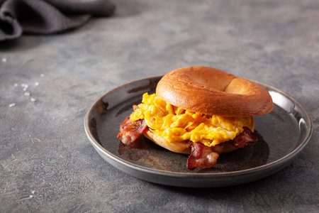 breakfast egg and bacon sandwich on bagel with cheeseの写真素材