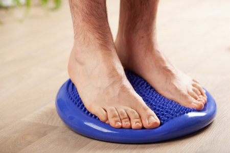 man doing flatfoot correction gymnastic exercise balancing on massage cushion at homeの写真素材