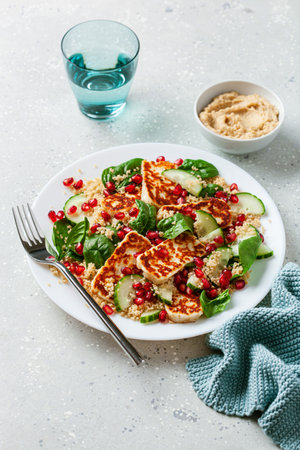 healthy halloumi cheese and couscous salad with cucumber spinach pomegranate hummusの写真素材