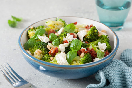 healthy broccoli salad with feta cheese sun dried tomatoes pine nuts. vegetarian low carb keto dietの写真素材