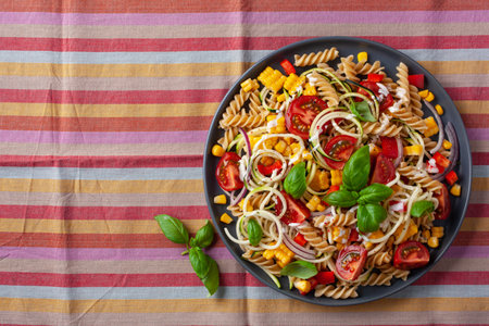 healthy pasta salad with zucchini sweet corn tomato and basil, vegetarian lunchの写真素材