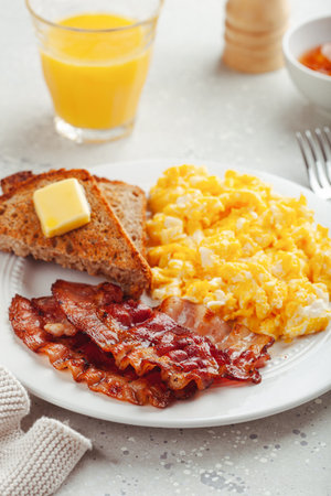 traditional scrambled egg breakfast with bacon and toastの写真素材