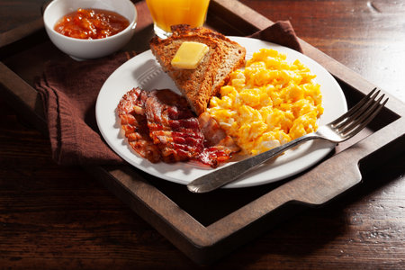 traditional scrambled egg breakfast with bacon and toastの写真素材