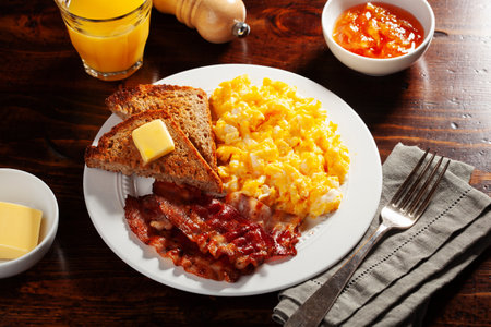 traditional scrambled egg breakfast with bacon and toastの写真素材