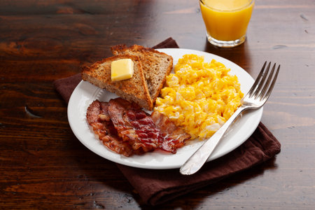 traditional scrambled egg breakfast with bacon and toastの写真素材