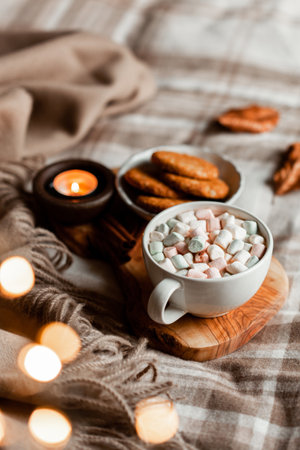 warm cozy bedroom interior with cup of hot chocolate on tray, candles christmas lightsの写真素材