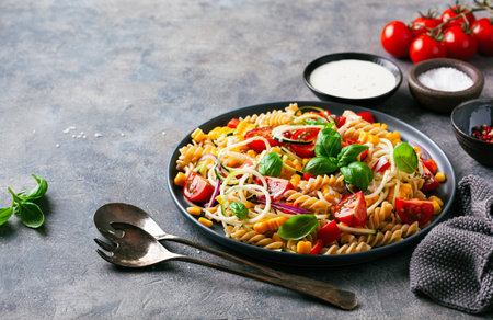 healthy pasta salad with zucchini sweet corn tomato and basil, vegetarian lunchの写真素材