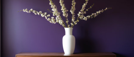 Elegant plant with white and purple flowers in a white vase, placed against a rich purple wall. Perfect for interior design and floral decor themes.の素材