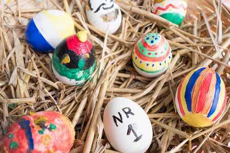 Painted Easter eggs in a basket with straw.の写真素材