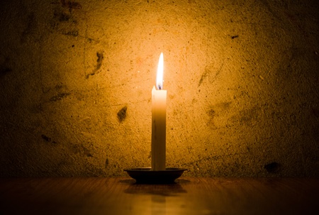 A candle burning, grungy wall background and vignetteの写真素材
