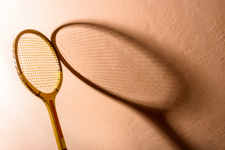 Backlit vintage tennis racket and its shadow on a pink backgroundの写真素材