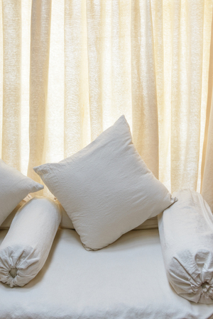 White sofa and cushions, backlit curtain backgroundの写真素材