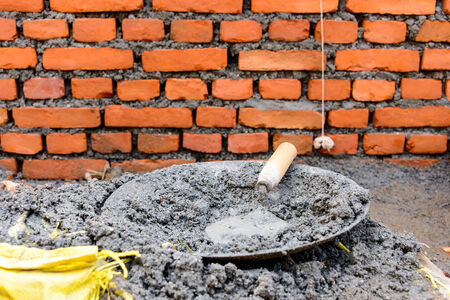 Trowel in fresh cement to build a brick wallの写真素材