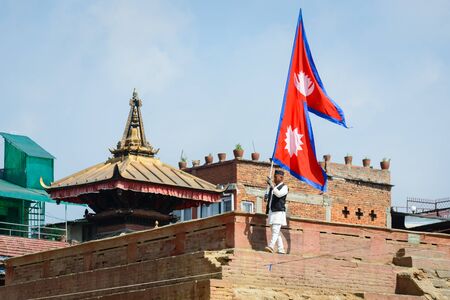 KATHMANDU NEPAL  MAY 14 2015: A man carries a large Nepal flag on Durbar Square a UNESCO World Heritage Site.のeditorial素材