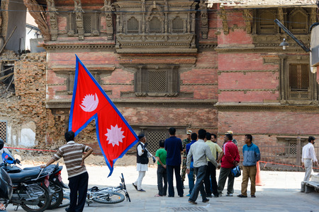 KATHMANDU, NEPAL - MAY 14, 2015: A man carries a large Nepal flag on Durbar Square, a UNESCO World Heritage Site.のeditorial素材